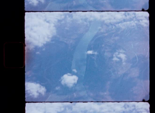 Vintage 8mm footage shows an aerial view of a vast river delta from high above the clouds