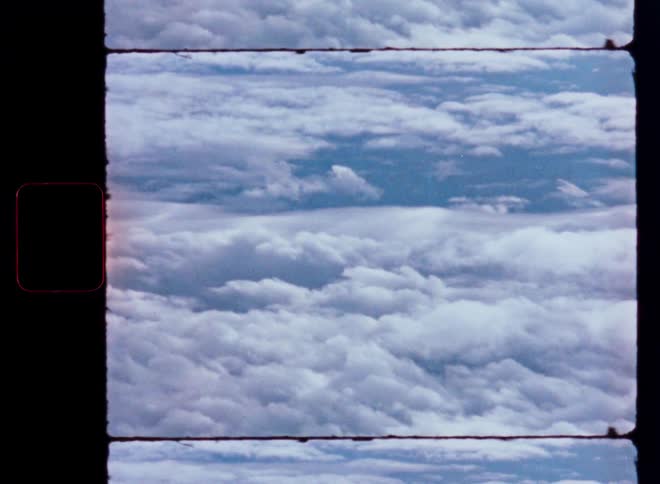 A static vintage film strip captures an aerial view of a serene and expansive cloudscape from above