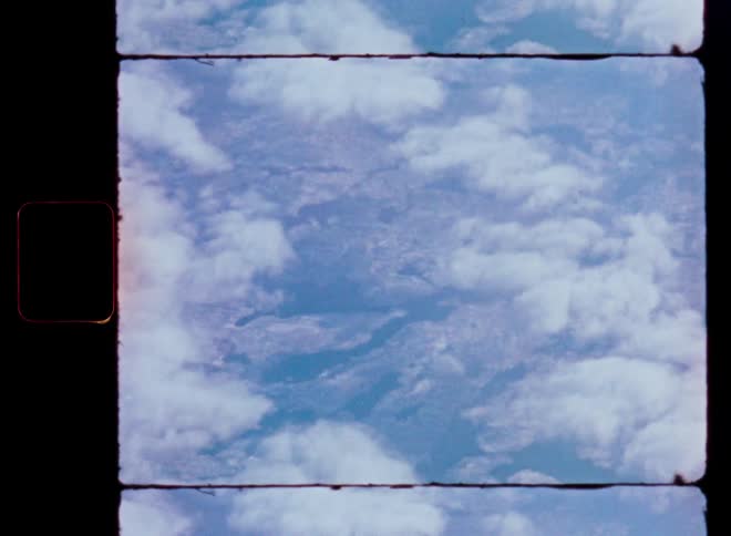 A static Super 8mm film frame shows an aerial view of clouds floating over a vast landscape with vintage light leaks