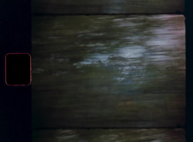 Vintage 8mm film captures a dreamy, motion-blurred view of a snow-capped mountain range from a passing vehicle