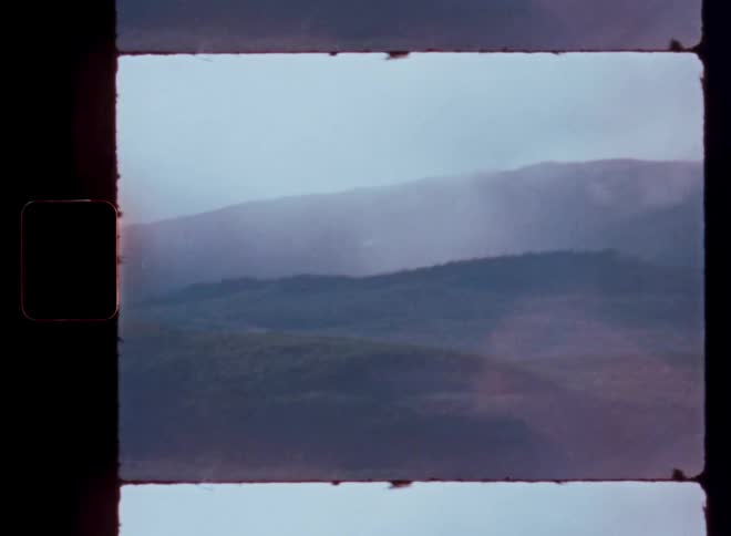 Atmospheric view of a hazy mountain landscape with rolling hills captured on vintage film