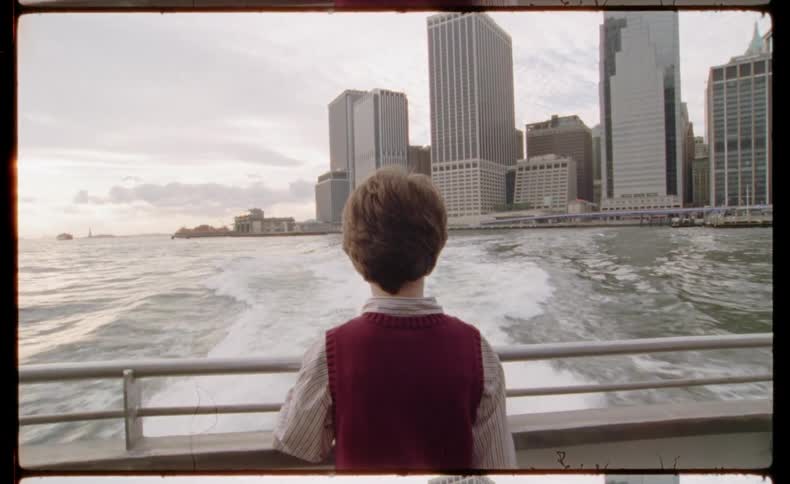 Vintage film shot from behind a person on a ferry watching the New York City skyline as the boat moves away across the water