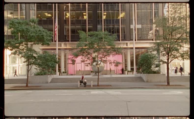 A vintage film-style shot captures the daily life of pedestrians, cyclists, and scooter riders in front of a modern skyscraper in New York City
