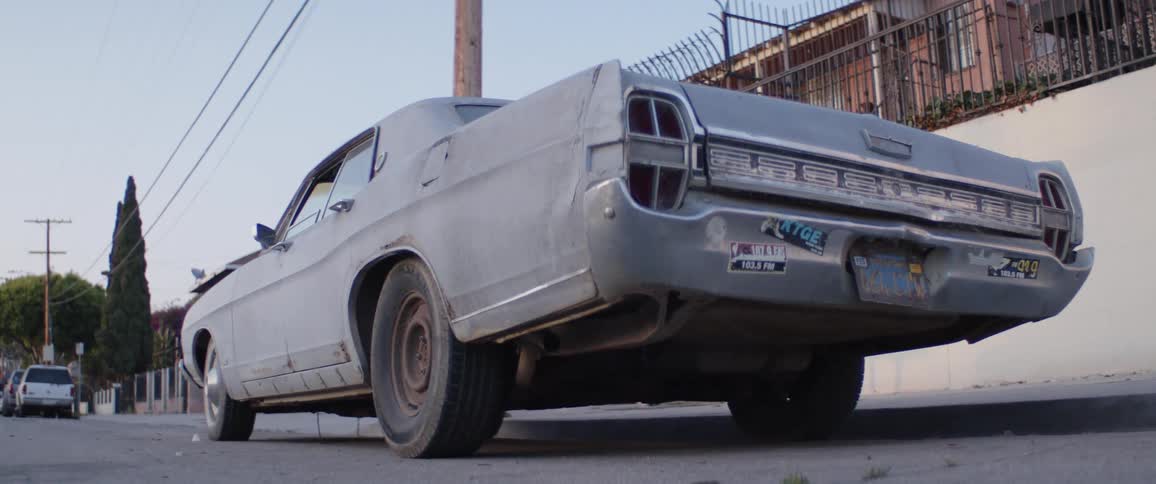 A low-angle shot of a classic, weathered American sedan parked on the side of a residential street