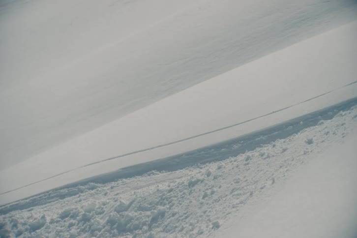 A high-speed skier carves through fresh powder on a vast mountain slope in a dynamic motion blur shot