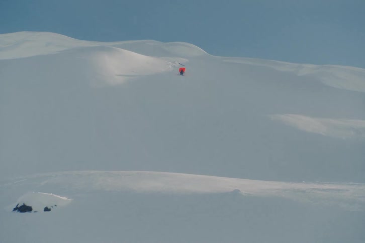 A skier crashes off remote snowy ridgeline and airbag releases, while ski takes off down mountain