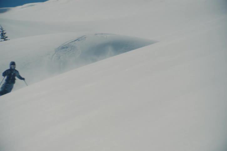 An expert skier glides through fresh powder down a vast, untouched mountain slope in slow motion