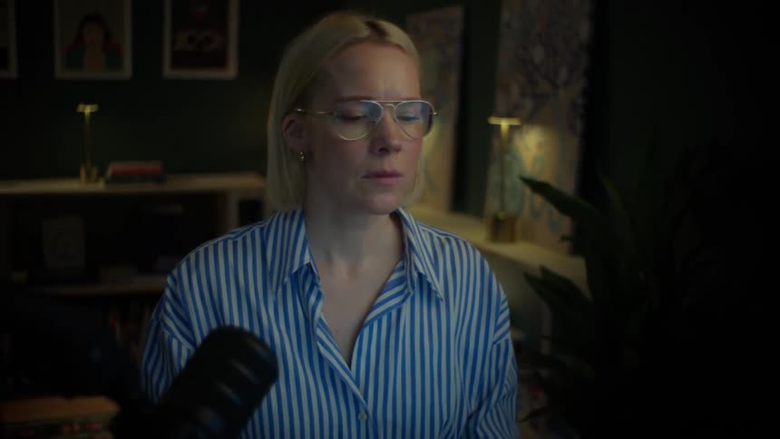 A concerned woman in glasses works late at night in her stylish home office, showing signs of stress and fatigue