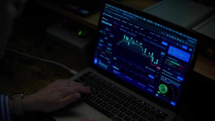 A trader monitors the volatile cryptocurrency market on a laptop screen in a dark room