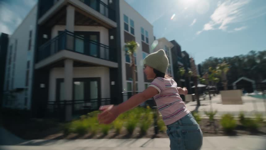 Slow motion tracking shot of a joyful young girl with her arms outstretched roller skating on a sunny day