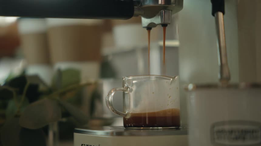 Close-up of a modern espresso machine pouring a freshly brewed double shot of coffee into a glass mug