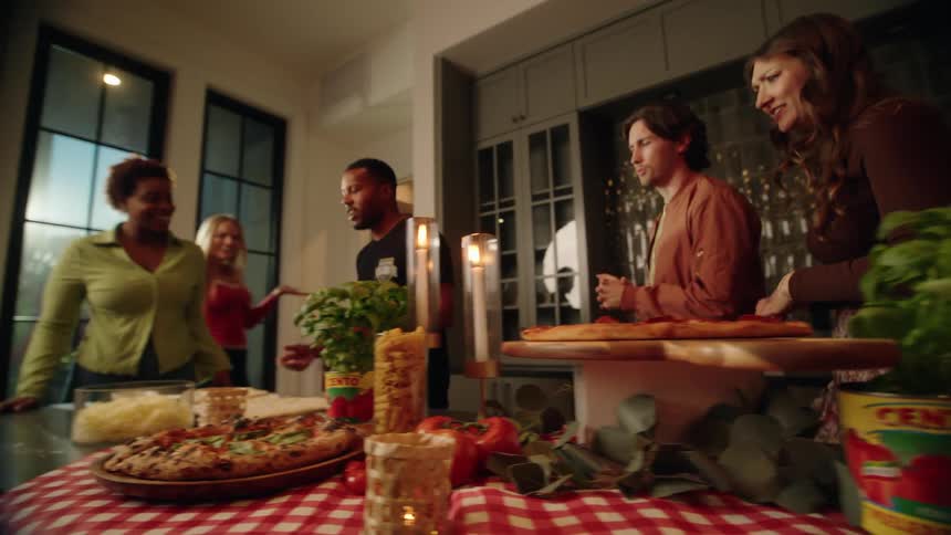 A diverse group of friends gathers in a modern kitchen for a lively pizza-making class with an instructor