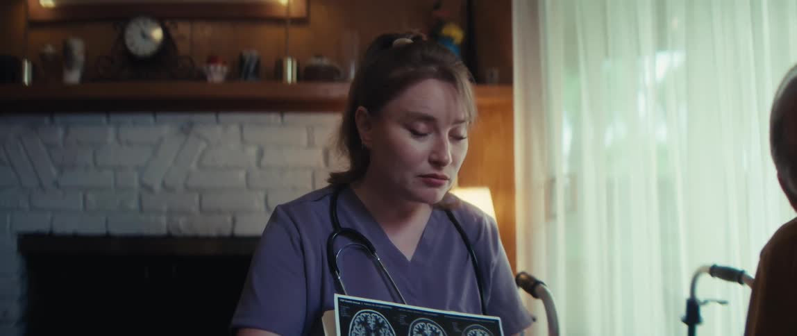 A compassionate home nurse delivers reassuring news to an elderly man after reviewing his brain scans in his living room
