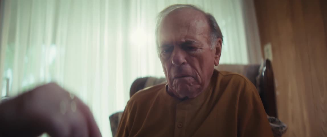 A caregiver helps an elderly man review a comprehensive care brochure in a sunlit room