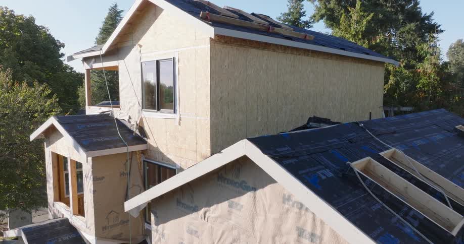 Pullback reveal of a new home under construction about to have roofing shingles installed