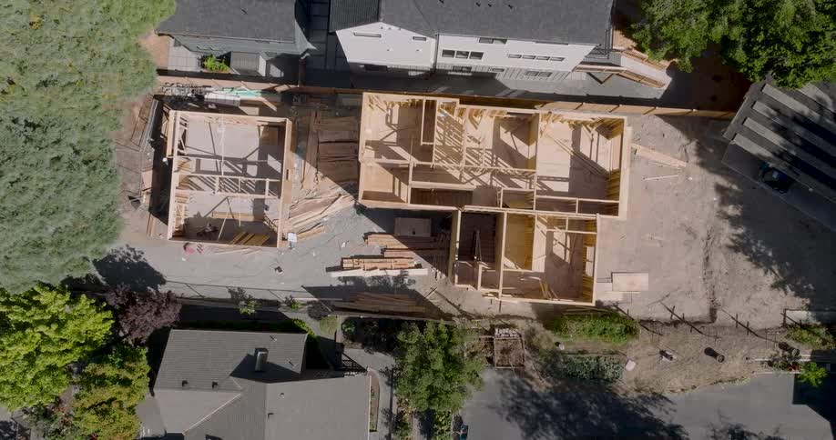 Slow and twisting descent over the narrow lot of a new house under construction
