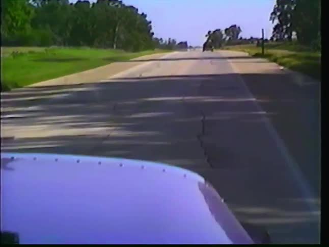 Vintage VHS footage shows a truck driving past the 'Iowa - You make me smile' welcome sign on a rural highway