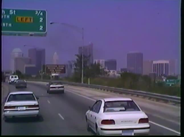 A vintage VHS point-of-view shot driving on a highway towards the Columbus, Ohio skyline during the day