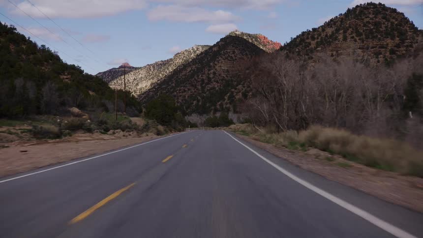 Driving pov down a winding mountain road through a scenic desert canyon in the American Southwest