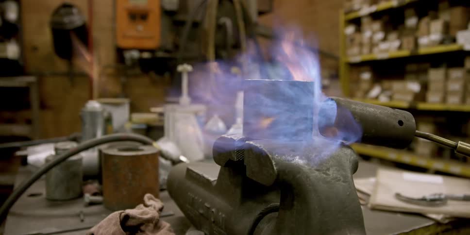 A person is torching metal in a vice