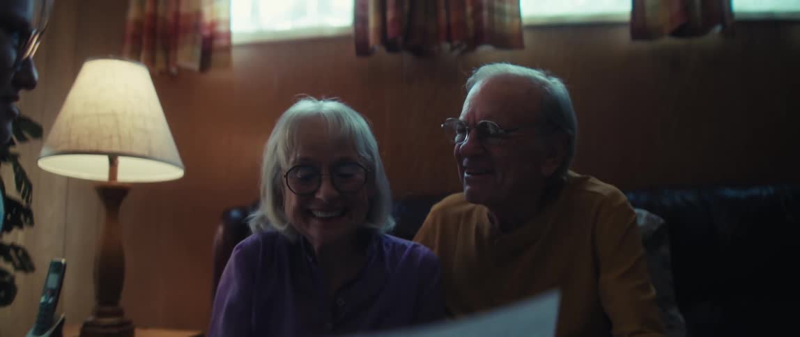 An overjoyed elderly couple laughs and smiles after reviewing a positive financial report together at home