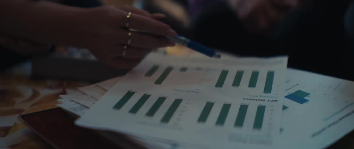 Financial advisors review and analyze printed bar chart data on MPT statistics during a business meeting
