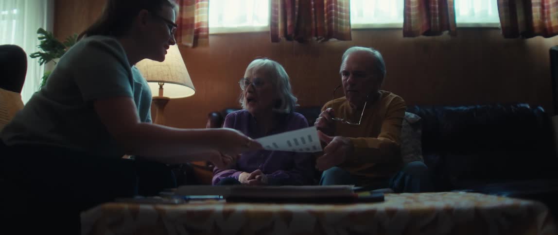 A financial advisor congratulates a happy senior couple after reviewing their successful investments in their living room