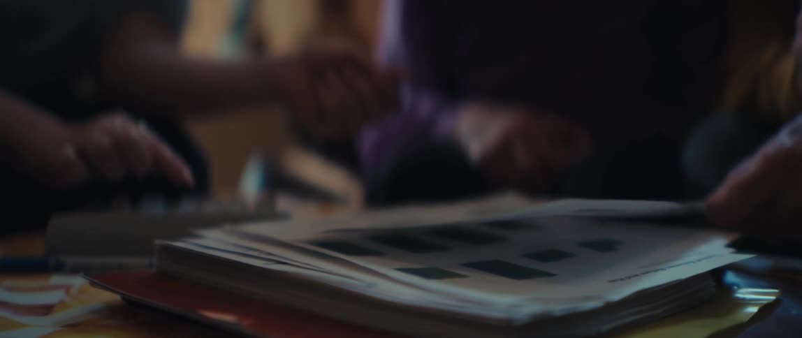 A slow-motion rack focus shot reveals colleagues analyzing financial data on printed bar charts during a business meeting