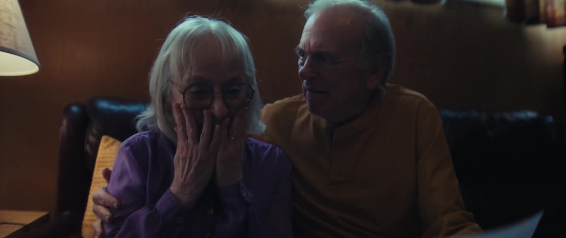 A financial advisor shares good news with an elderly couple, whose initial concern transforms into joyous relief and laughter