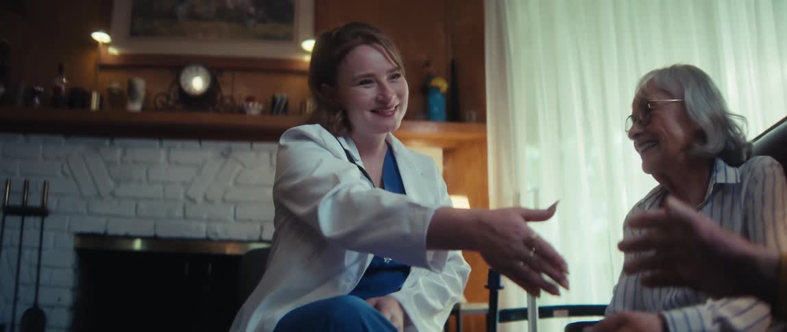 A friendly female doctor smiles warmly as she comforts and shakes hands with a happy elderly couple during an in-home health visit