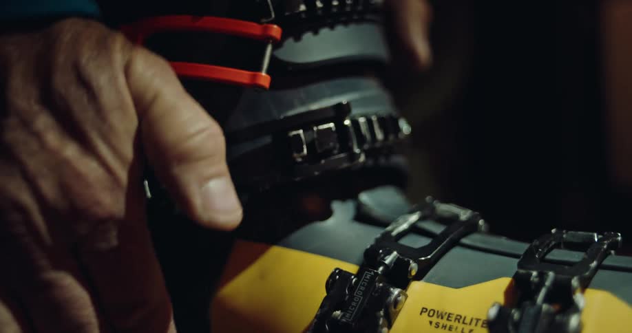A skier fastens the buckles on their ski boot in a detailed close-up shot