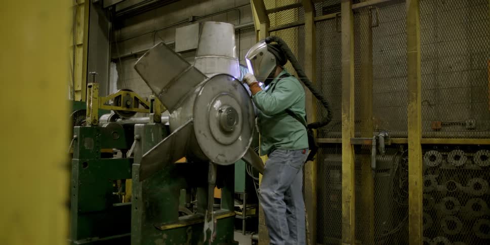 A man works in a shop welding with a mask on