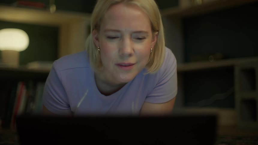 Overwhelmed woman working from home at night takes off her glasses and squints at her laptop, feeling stressed and tired