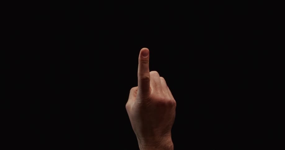 A man's hand with his index finger extended makes a gesture of disapproval by shaking it from side to side against a black background