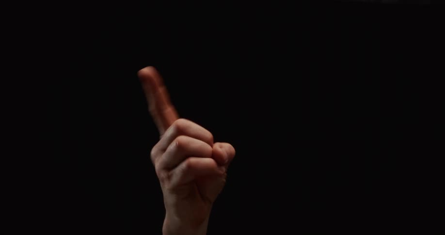 A hand wags its index finger back and forth in a gesture of negation against a solid black background