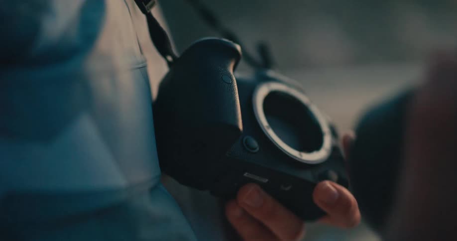 Close-up slow-motion shot of a photographer detaching a lens from a digital camera body