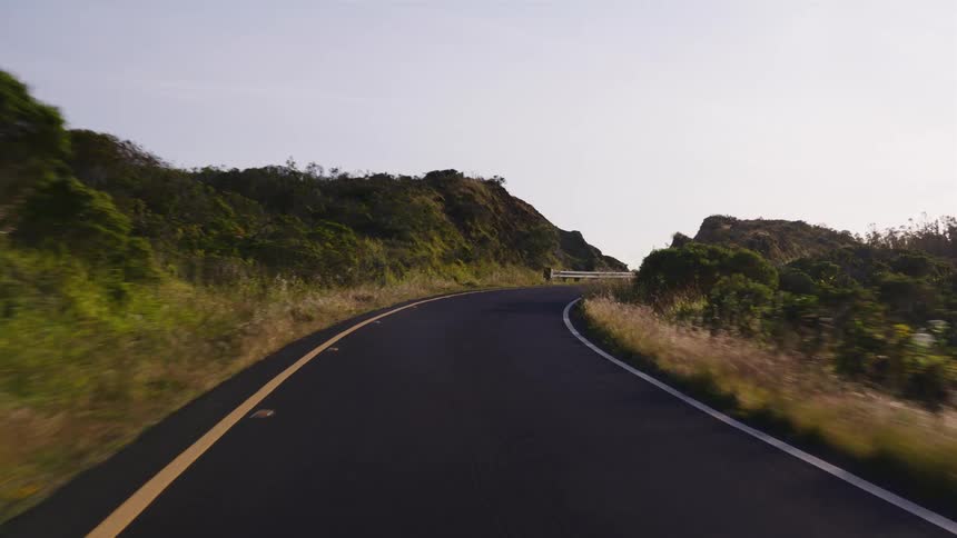 A scenic point-of-view drive along a winding country road through sunlit green hills