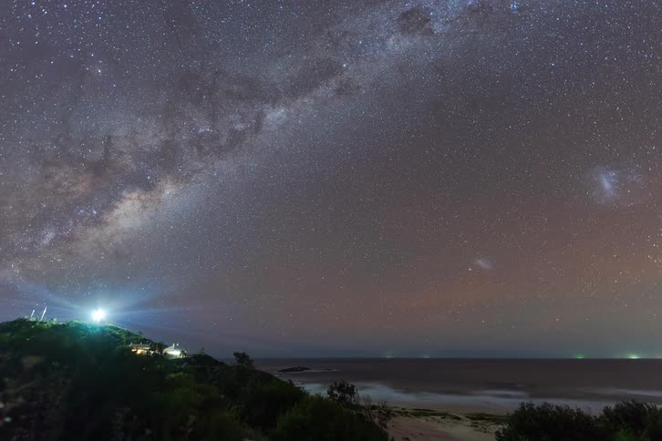 A stunning time-lapse captures the Milky Way galaxy moving across the starry night sky over a coastal lighthouse and the ocean
