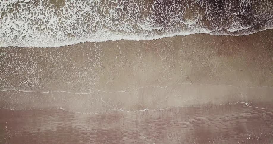 Waves crash against the shore on a sunny day