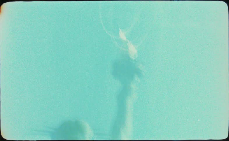Shaky and abstract vintage film footage reveals the torch of the Statue of Liberty against a blue sky