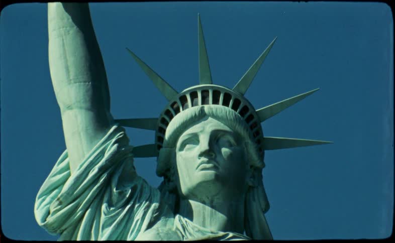 A vintage, low-angle close-up of the iconic Statue of Liberty's face and crown set against a vivid blue sky