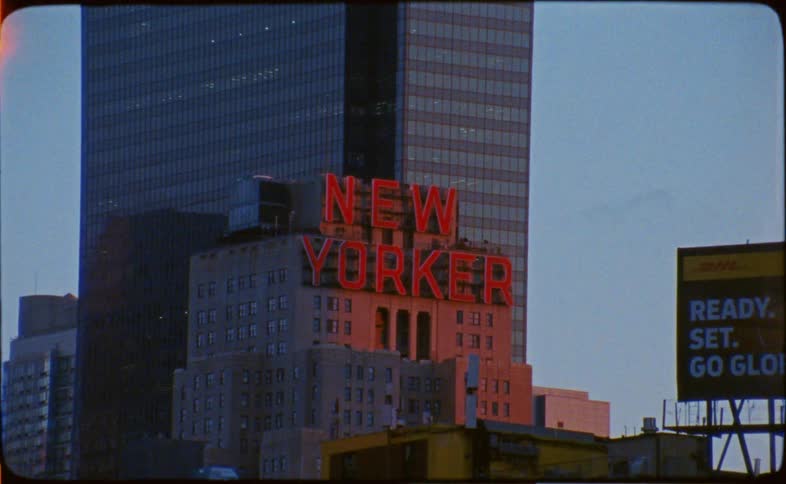 Vintage film footage reveals the iconic New Yorker Hotel sign glowing red against the Manhattan skyline at dusk