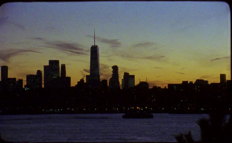 Vintage Super 8mm film captures the silhouetted New York City skyline over the water at dusk, ending with an abstract shaky camera effect