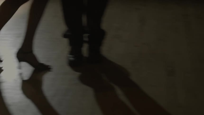 A man and woman dance on a wood floor