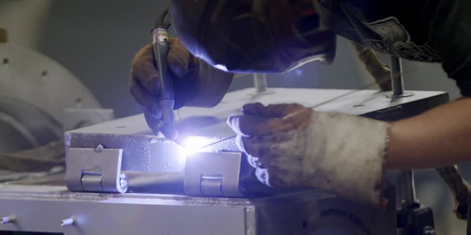 A welder leans over to work