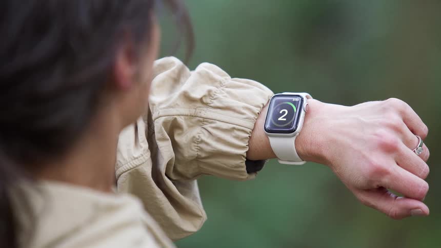 Over the shoulder shot of a woman starting a workout on her smartwatch while outdoors in nature