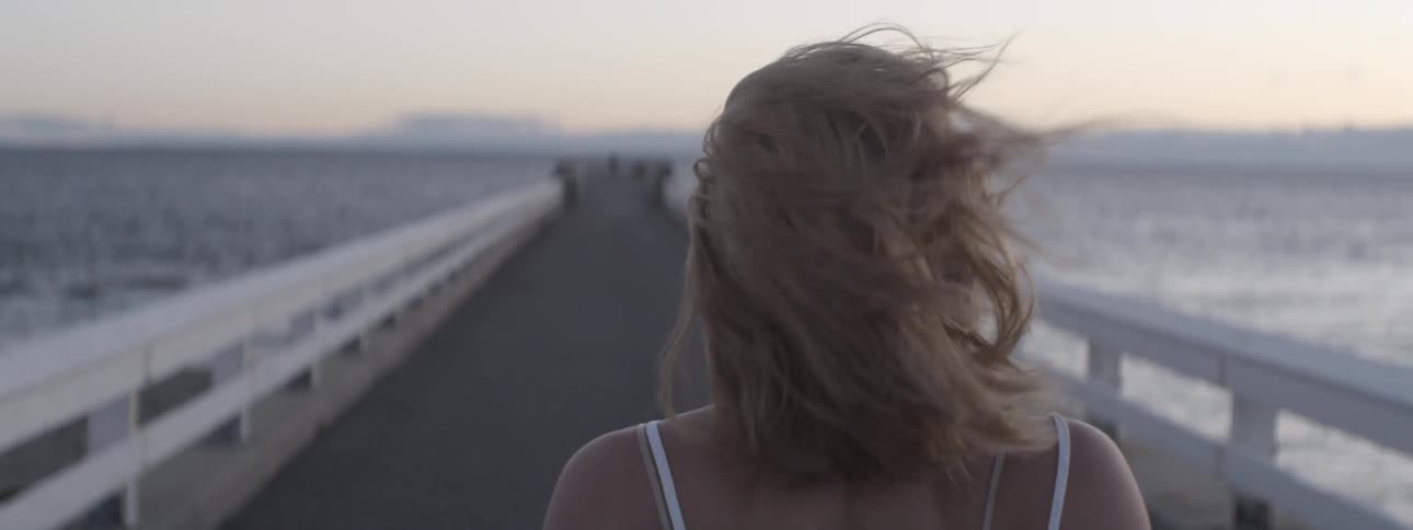 A woman walks down a windy pier