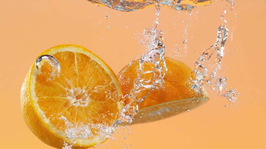 Vibrant halved orange submerged in water, creating beautiful bubbles in artistic slow motion