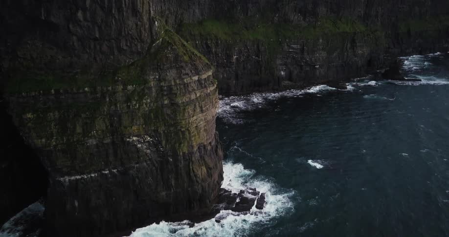 Waves lap the base of very tall cliffs