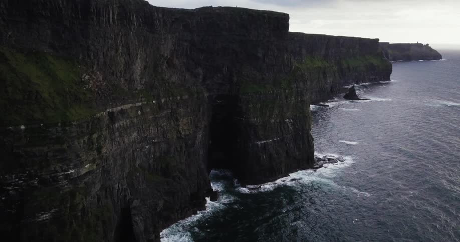 Waves crash against the very tall cliffs